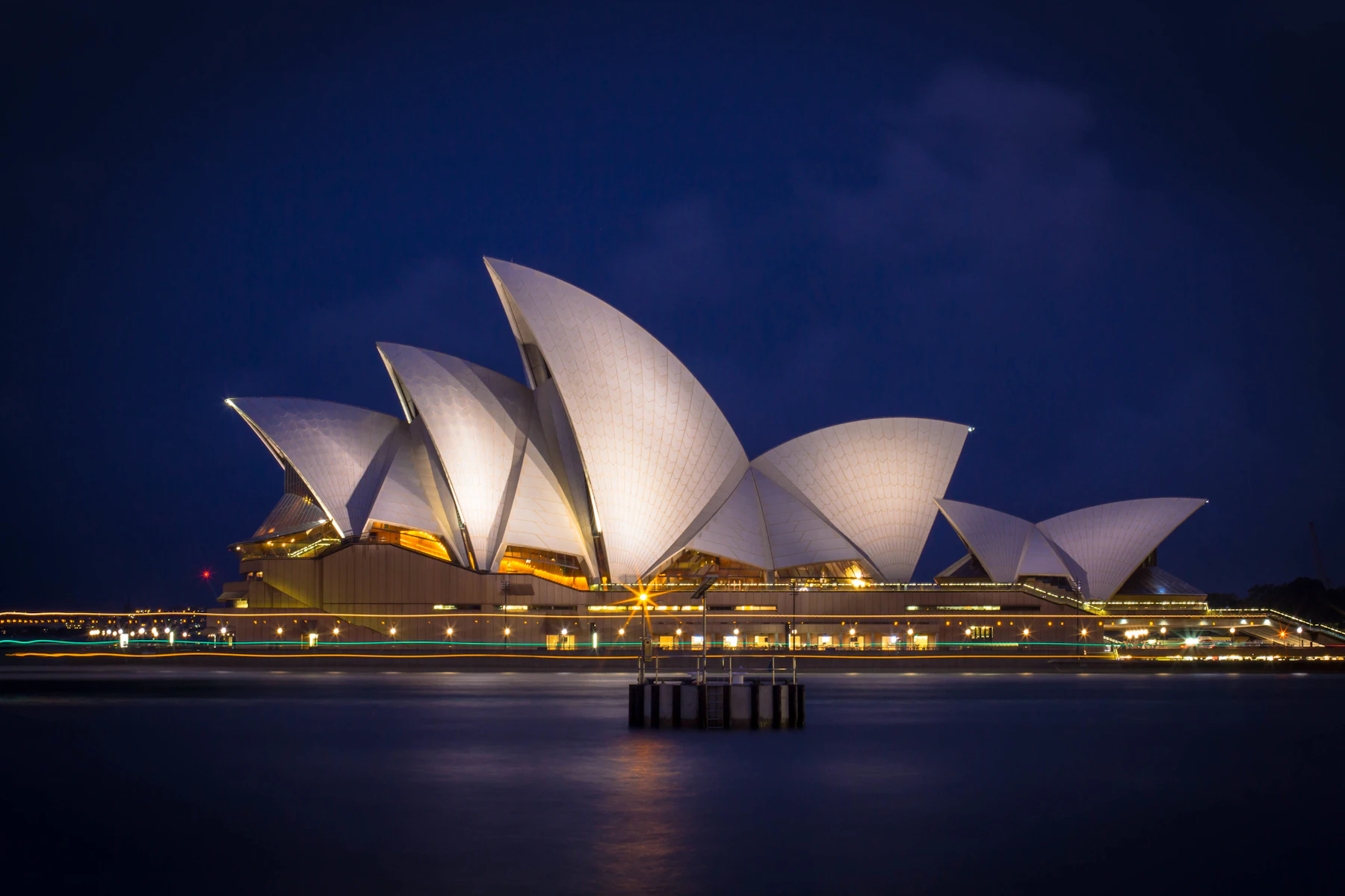 Sydney Opera House illuminated across the harbour at night