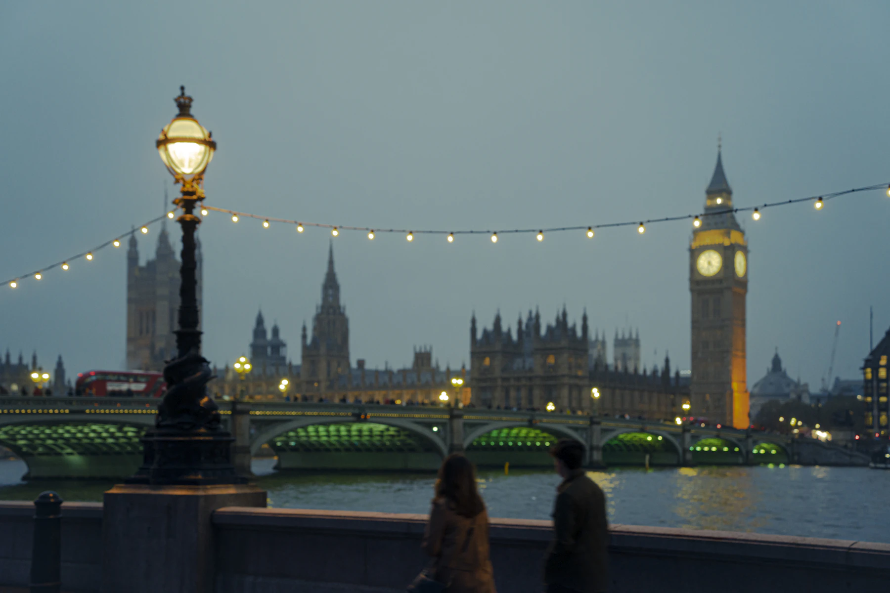 Big Ben and Westminster glowing beside the Thames at dusk