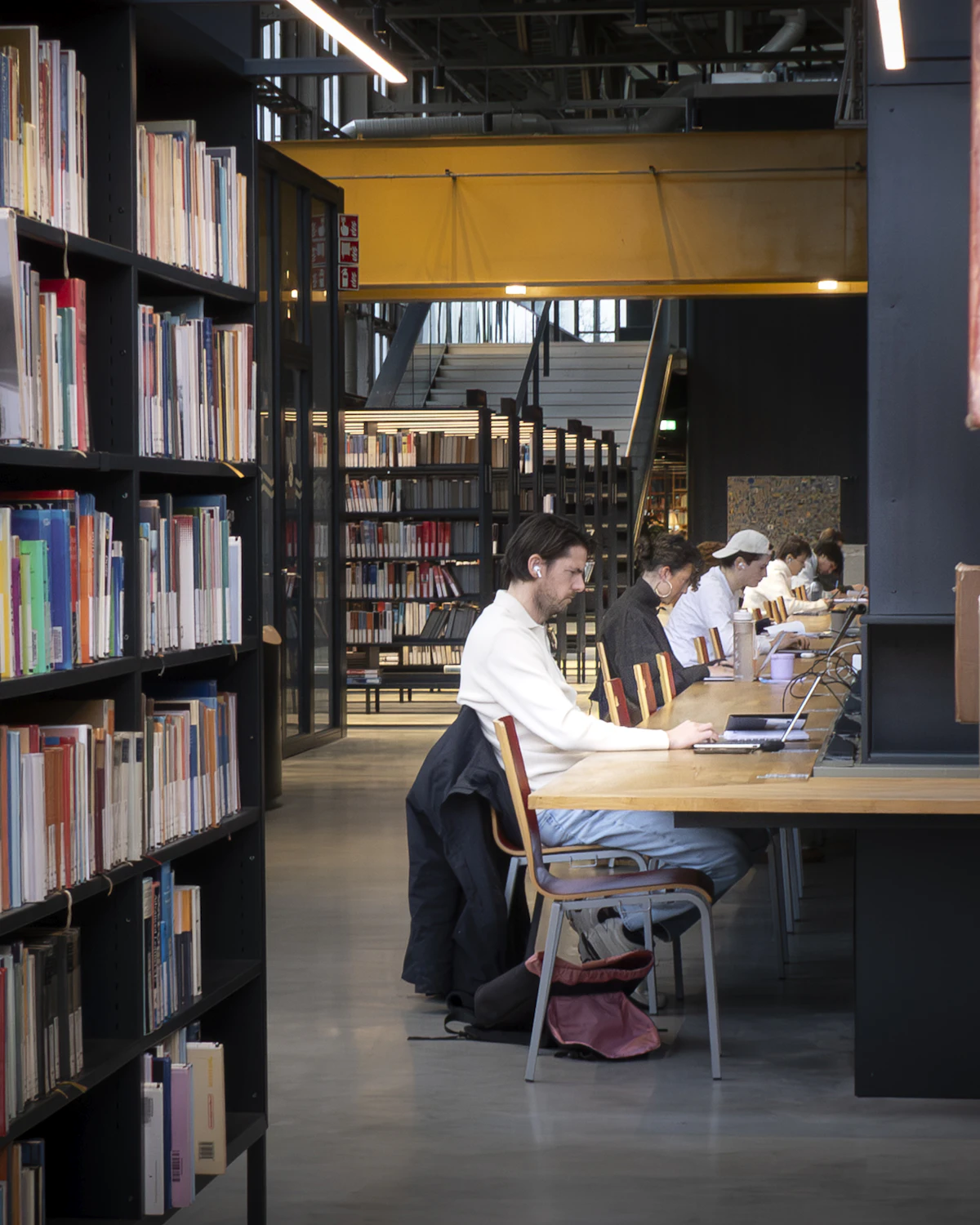 Students working quietly at a long table in a university library
